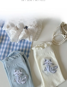 Détail de chaussettes brodées chat avec bordure à volants en bleu et crème
