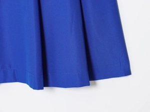 Gros plan sur l'ourlet plissé d'une jupe midi bleu roi en tissu sergé de qualité