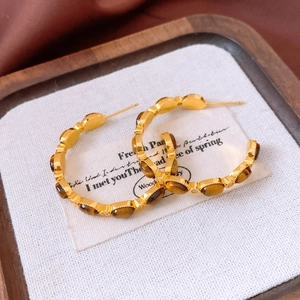 Close-up of vintage C-shape earrings with tiger eye stone and 18K gold plating