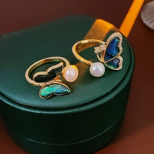 Detailed view of butterfly rings with gold plating, colorful shells and freshwater pearls