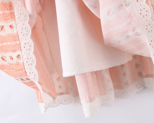 Dettaglio dell'orlo in pizzo e fodera bianca di un abito rosa a motivi floreali