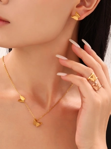 Detail view of gold butterfly jewelry set including necklace, earrings and rings on model