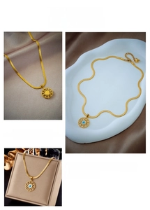 Detail of gold snake chain necklace featuring a hollow sun pendant with blue evil eye stone
