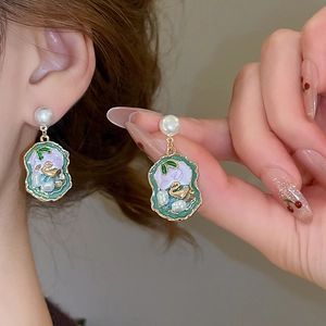 Detail of vintage enamel earrings with pearl studs and golden swan relief pattern