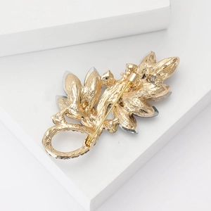 Detail view of the gold leaf brooch back structure and secure pin on a geometric stand