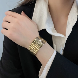 Detailansicht eines breiten, goldfarbenen Manschettenarmbands mit Wellenstruktur