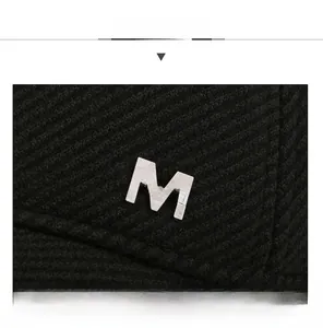 Macro view of M SPORT metal logo on black striped fabric of a winter baseball cap
