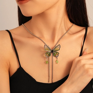 Detail of vintage butterfly pendant with green crystals and tassel on a long chain