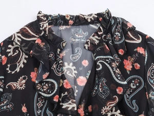 Detail of V-neck ruffled collar on black paisley chiffon dress with floral patterns
