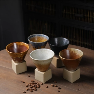 Japanese style ceramic coffee drippers in five vintage colors on a rustic wooden table
