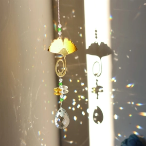 Golden ginkgo leaf suncatcher with crystal pendant casting rainbows on wall