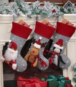 Three Christmas stockings with 3D Santa, reindeer, and penguin hanging by the fireplace