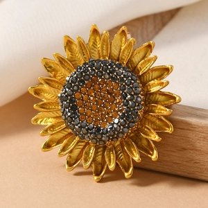 Elegant gold sunflower brooch with black and amber rhinestones on a rustic wood base