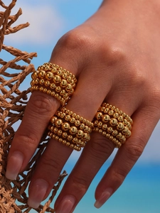Three-piece set of gold multi-layer bead rings shown in a stacked style on a hand