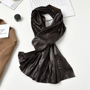 Deep brown pleated leather scarf for women with glossy finish on a white table set