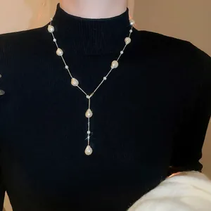 Elegant gold-plated pearl Y-necklace with baroque pearls on a black turtleneck sweater