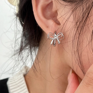 Close-up of a silver bow-shaped ear cuff showing metallic texture on a model ear