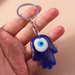 Macro detail of Hamsa Hand evil eye charm in blue glass with silver metal keyring