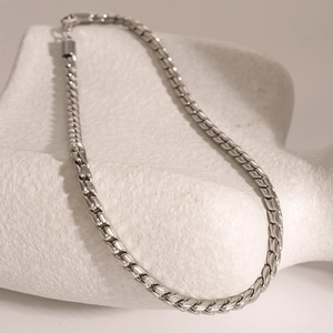 Detail shot of a silver 5mm stainless steel flat snake chain on a white stone pedestal