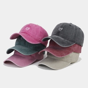 Detailed stack of vintage washed cotton baseball caps with small heart embroidery in 6 colors