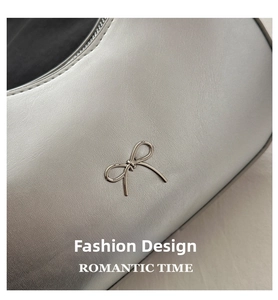Macro detail of silver leather bag featuring a polished metal bow buckle and fine stitching