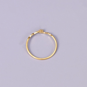 Minimalist gold wavy line ring with a small round diamond on a soft purple background