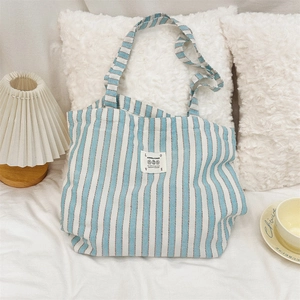 Detailed close-up of a blue striped canvas tote bag with woven labels in a cozy home setting