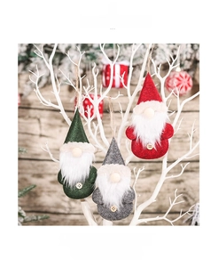 Close-up of Nordic gnome ornaments in red, green and grey hanging on a white branch