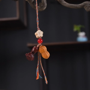 Detailed view of hand-woven cord with peanut wood carving and red agate bead charm