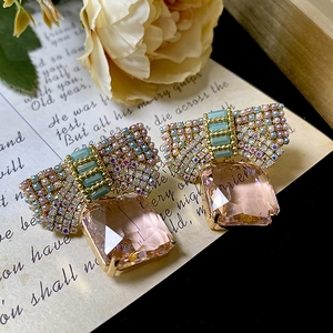 Pink bow crystal earrings with multicolored stones on vintage manuscript background