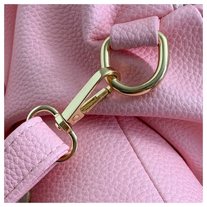 Close-up of pink PU leather texture with gold metal hook and D-ring buckle on backpack