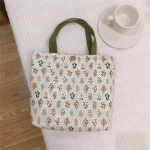 Détail du sac déjeuner en coton fleuri avec poignées vertes et fermeture aimantée en métal