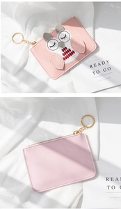 Pink coin purse with owl embroidery and key chain hook on white fabric backdrop