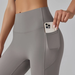 Detail showing high-waisted yoga pants with side pockets holding a smartphone