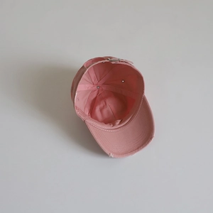 Detail of pink cotton baseball cap interior showing distressed brim and metal buckle