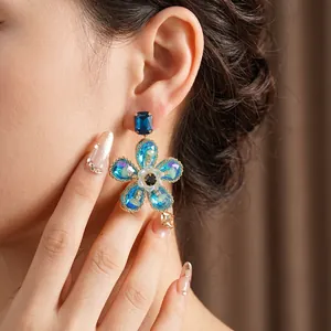 Boucles d'oreilles vintage fleurs dorées avec cristaux bleus portées par un mannequin