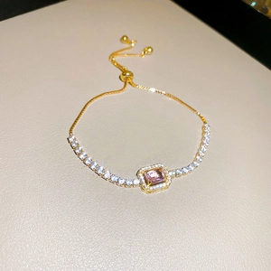 Detail of adjustable gold bracelet with pink rectangular stone and zircon inlay