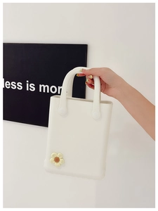 Detail einer cremeweißen EVA-Tasche mit einem 3D-Blumen-Accessoire in Gelb und Weiß