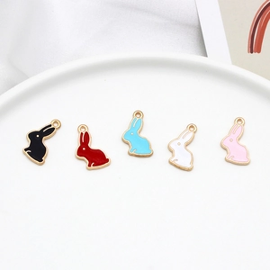 Five colorful rabbit alloy pendants on a white plate for DIY jewelry making and crafts