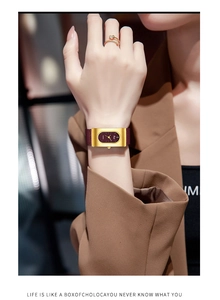 Detail of elegant rectangular gold watch with wine red leather strap on model wrist