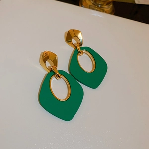 Gros plan détaillé des boucles d'oreilles géométriques rétro en vert et doré
