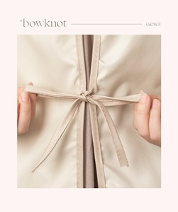 Detailed view of hands tying a beige bowknot on the back of a waterproof kitchen apron