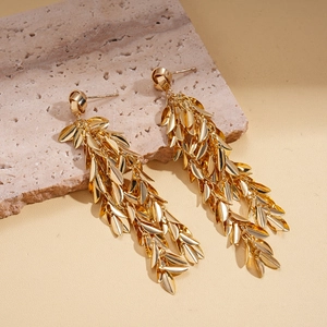 Detailed view of gold leaf tassel drop earrings on a natural stone display base