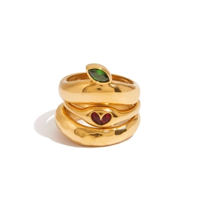 Detailed stack of three gold rings with emerald marquise, heart ruby, and hammered texture
