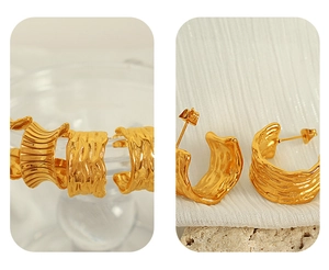Detailed close-up of gold C-shaped earrings with unique hammered pleated texture