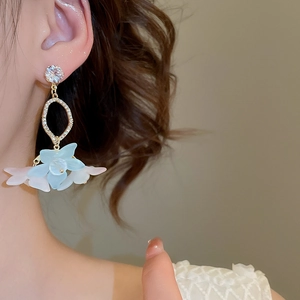 Close-up of elegant flower drop earrings with blue petals and sparkling zircon studs on model