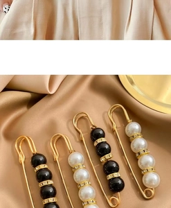 Detailed close-up of gold geometric brooches with pearls and rhinestones on beige silk