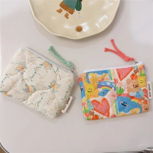 Detailed view of quilted cotton coin purses with floral and cartoon patterns and zipper pulls