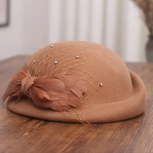 Detailed view of camel wool hat with mesh veil, elegant feathers and a sparkling bow