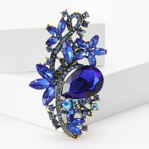 Detailed close-up of a vintage gold alloy brooch featuring deep blue crystals and teardrop gems